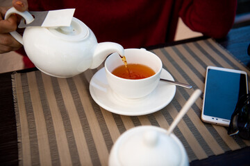 Teapot cup of tea and smartphone on the table. Close-up.
