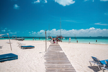 Cancun, Mexico. May 30, 2021. Wooden pier leading from sand into sea with moored yachts or sailboat...