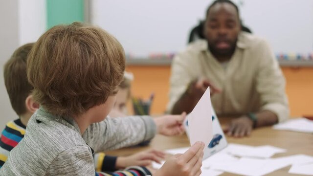 An African American teacher teaches a group of children numbers using flashcards.School for Children, Teaching Adolescents, Gain Knowledge, Learn the Language.