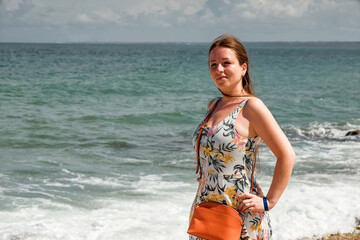 a girl in a summer dress on the seashore. Beautiful nature. Rocky shore. Journey.