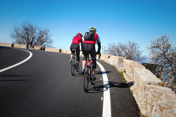 Couple of cyclists with a red T-shirt rides on the streets of Palma de Mallorca, in a sunny day. Spain, Europe.