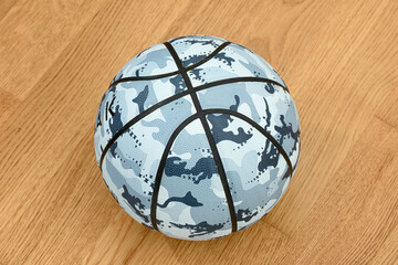 Camouflage basketball ball on wooden court background.