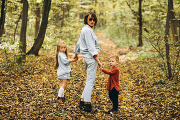 Fototapeta premium Mother with her little son and daughter in an autumn park