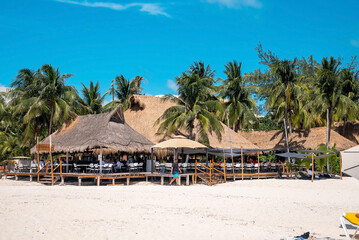 Cancun, Mexico. May 30, 2021. Tourists relaxing under straw canopy at restaurant on sandy beach during summer holiday