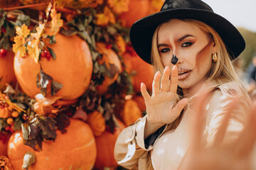 Woman with halloween make up standing by halloween pumpkins