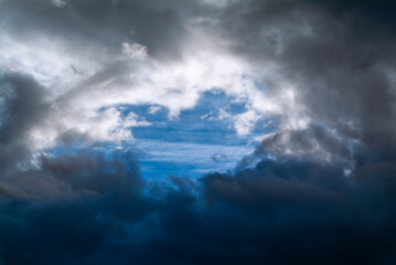 Naklejka na ściany i meble A hole in the dark clouds show a portion of blue sky