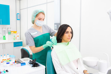 The dentist's assistant puts the protection on the patient, the napkin on the chest