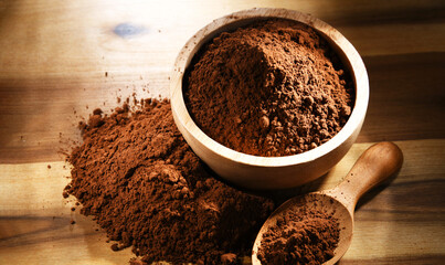 Composition with bowl of cocoa powder on wooden table
