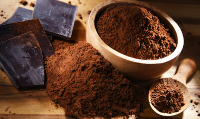 Composition with bowl of cocoa powder on wooden table