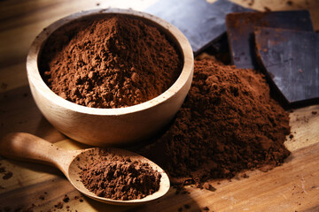Composition with bowl of cocoa powder on wooden table