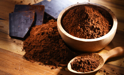 Composition with bowl of cocoa powder on wooden table