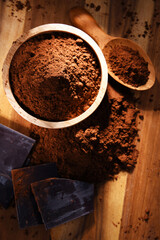 Composition with bowl of cocoa powder on wooden table