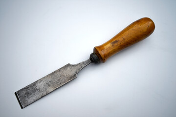 Forged metal chisel on wood with a wooden handle on white isolate. An antique hand tool for woodworking.