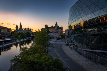 the Ottawa Convention Centre, at sunset, with Parliament and the Rideau Canal in the background