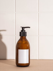 Amber bottle with white label mockup for bathing products in bathroom, spa shampoo, shower gel,...