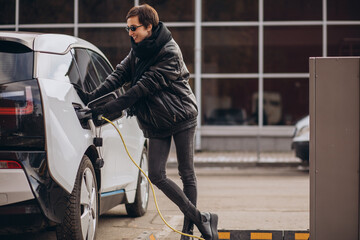Woman charging electro car at the street
