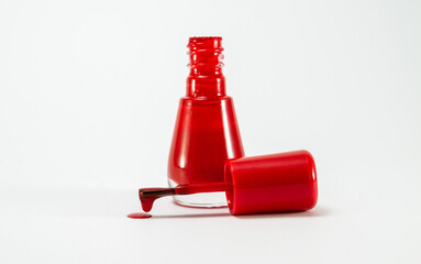 Red nail polish, glass bottle on a white background.