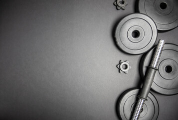 Heavy dumbbells weight plates. Gym flat lay composition with copyspace on black background.