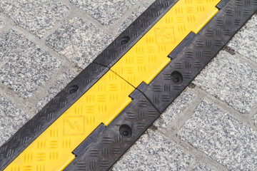 Cable protector cover. Yellow and black protective cable ramp for outdoor events.