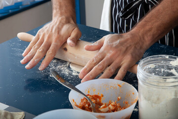 Manos  de chef amasando con rodillo masa de pizza. Chef hands kneading pizza dough with rolling pin