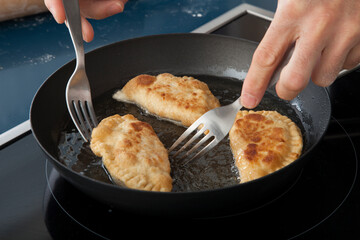 Empanadillas fritas en sartén. Fried dumplings in a frying pan. - obrazy, fototapety, plakaty