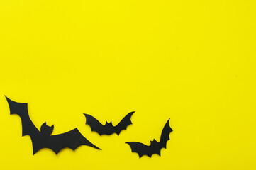 Halloween and decoration concept - black bats on yellow background. Folded paper origami...