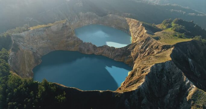 Volcano crater lake landscape aerial panorama. Blue water reservoir in morning sunrise light. Nature background. Travel destinations. Beautiful wild landscape. Exotic summer vacation. Drone zoom out