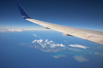 Fototapeta na wymiar airplane wing over Atolls island. Air travel concept
