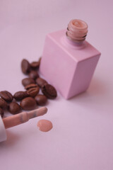 on a pale pink background, a pink jar of nail polish with coffee beans