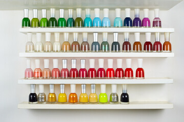 Set of different nail polishes on shelves against white background