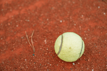 Yellow tennis ball on clay tennis court.