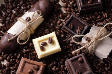 Pieces of black and white chocolate on the table, top view. The background is made of coffee beans.