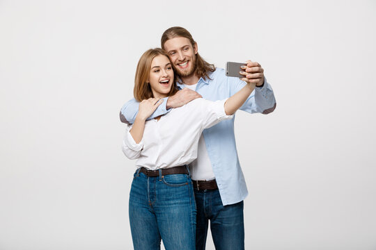 Portrait of a happy couple making selfie photo with smartphone over isolated white studio background.