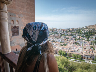 Back girl with blue & white hat looking at the town with white houses and blue ski