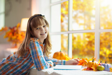Child at window in autumn. Kids at home in fall.