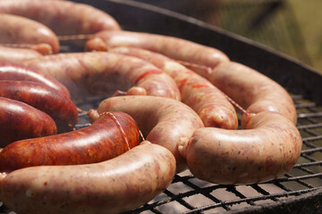 Fototapeta premium BBQ: close view of raw sausages on an outdoor grill