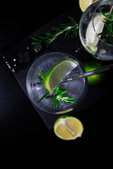 banner of classic gin and tonic cocktail with rosemary sprigs in tall glasses on a table with bar accessories