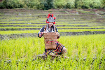 A hill tribe woman sitting in a field. A young woman in a hill tribe dress in a terraced rice field.