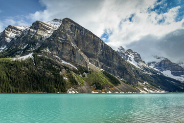 Emerald waters of Lake Louise in Banff National Park, surrounded by snow capped mountains.