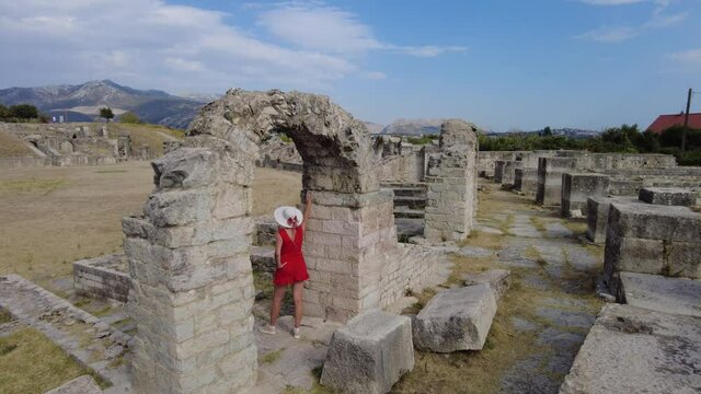 Tourist lady walking in the Salona ruins of the Ancient Roman Amphitheatre of Dalmatia in Croatia. Historic Roman coliseum ruins in Flavian architectural style.