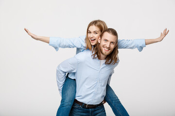 Portrait of smiling man giving happy woman a piggyback ride.