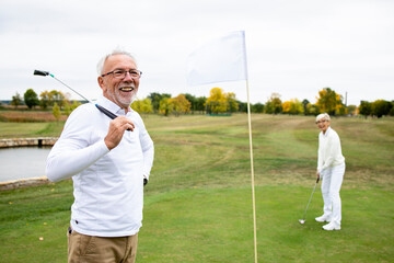 Portrait of an active senior man playing golf at the golf course and enjoying free time outdoors.