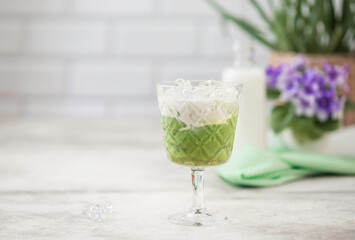 Cold Matcha green tea with ice cube and milk. Healthy eating concept. Pouring milk into a glass of green tea.
