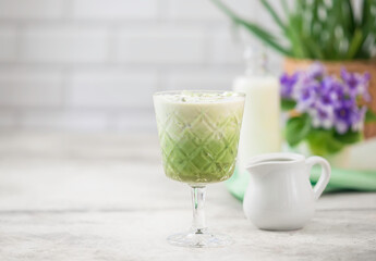 Cold Matcha green tea with ice cube and milk. Healthy eating concept. Pouring milk into a glass of green tea.