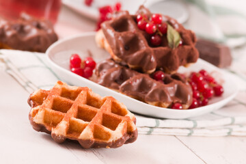 Waffles with chocolate topping, red currant and hazelnuts.