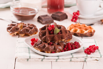 Waffles with chocolate topping, red currant and hazelnuts.