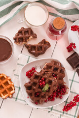 Waffles with chocolate topping, red currant and hazelnuts.