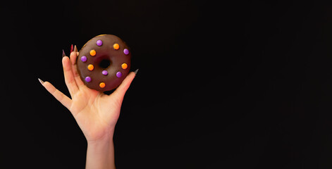 Female hands holding halloween donut isolated on black background with copy space