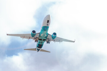 Low-flying passenger commercial plane in the cloudy sky after takeoff or going to landing flight. Vacation holiday travel. Air transportation background with copy space
