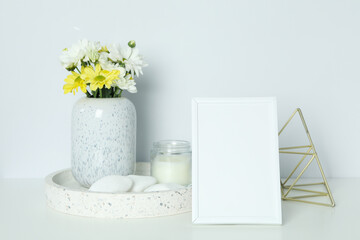Beautiful composition with chrysanthemums and empty photo frame on white table